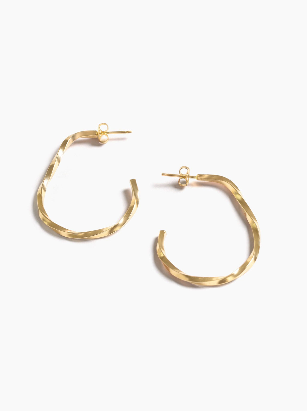 Gold hoop earrings lying on a white background.