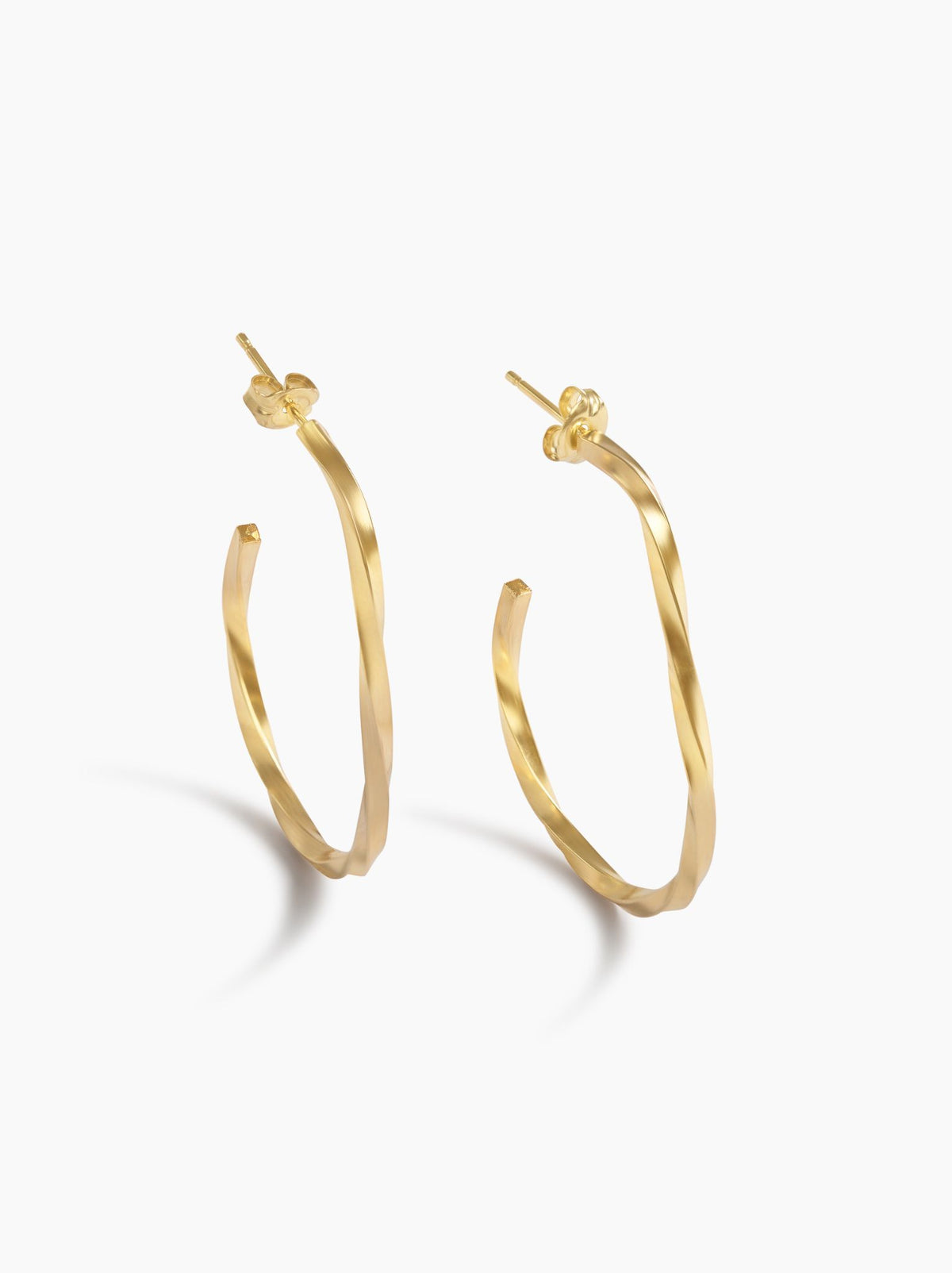 Gold hoop earrings standing up on a white background.