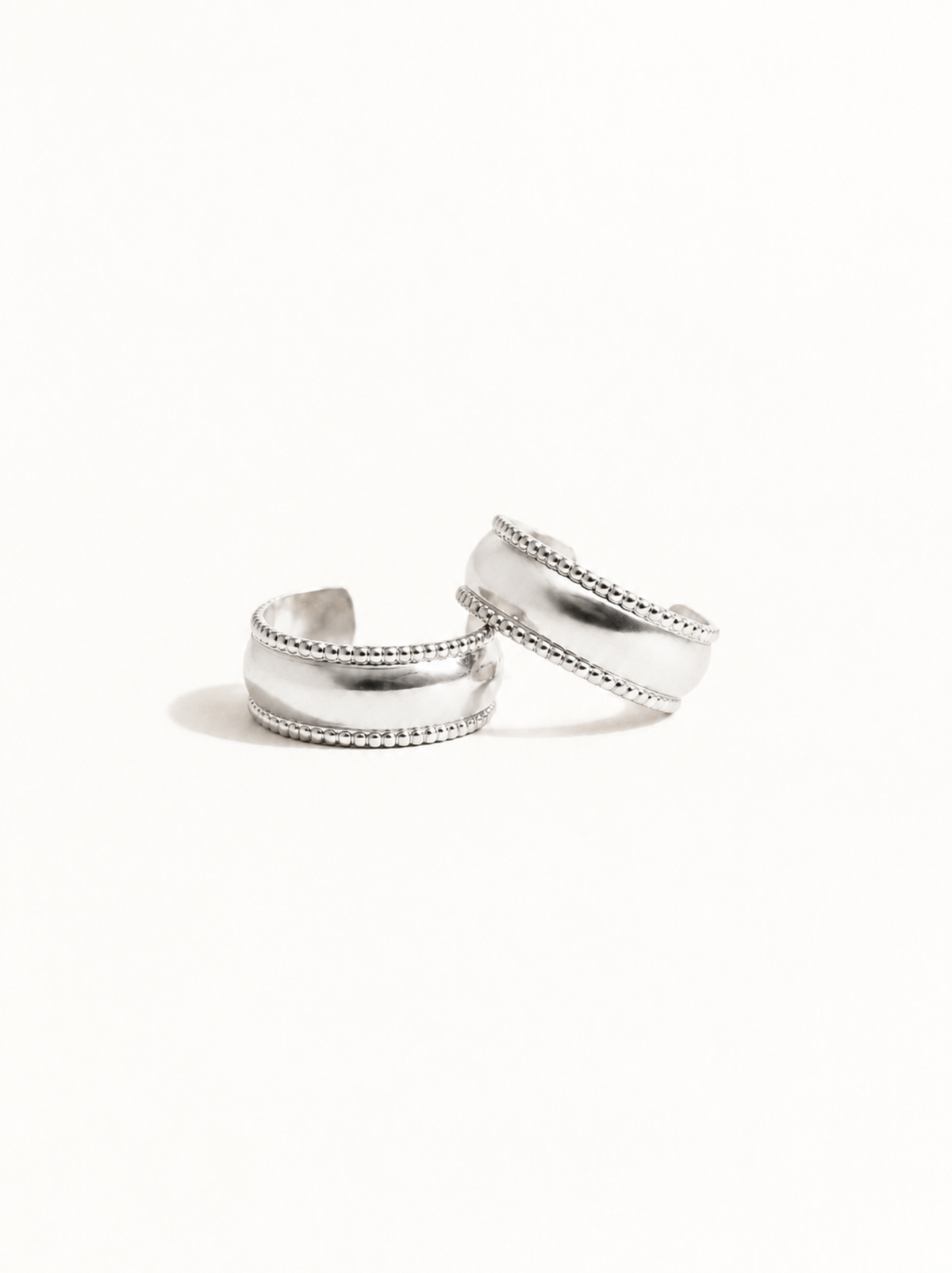 Two silver hoop earrings on top of each other, showing their textured edges on a white background. #Color_Sterling Silver