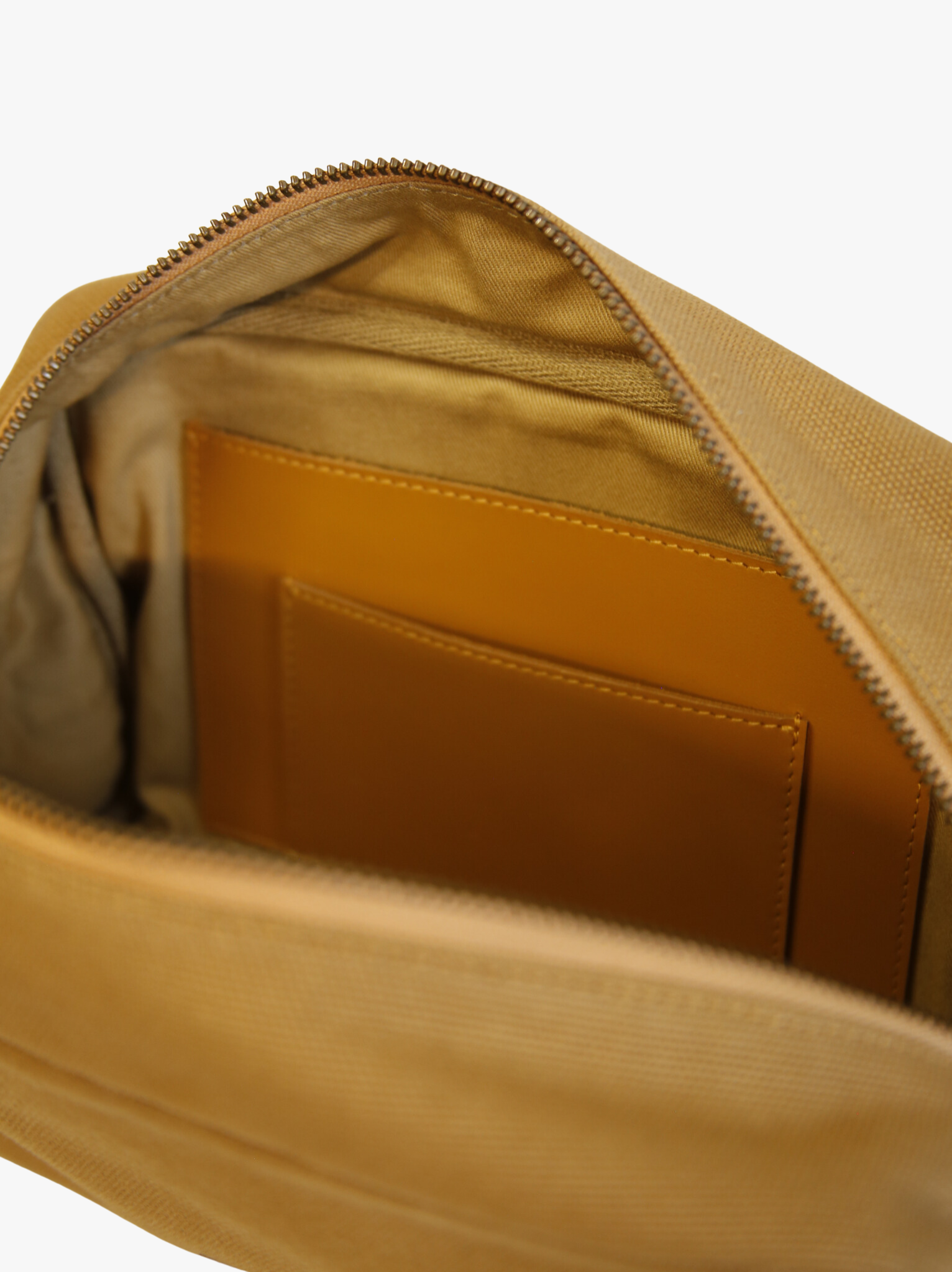 Close-up of a tan canvas bag with a zipper, showing the interior pocket.