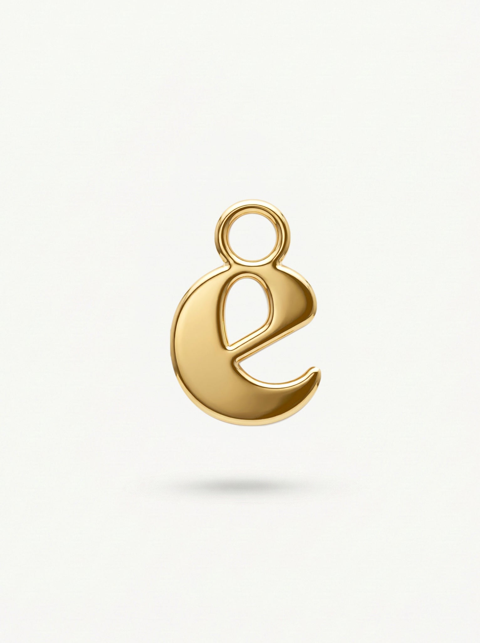 Initial Charm Gold Vermeil; Gold letter 'e' pendant on a light beige background