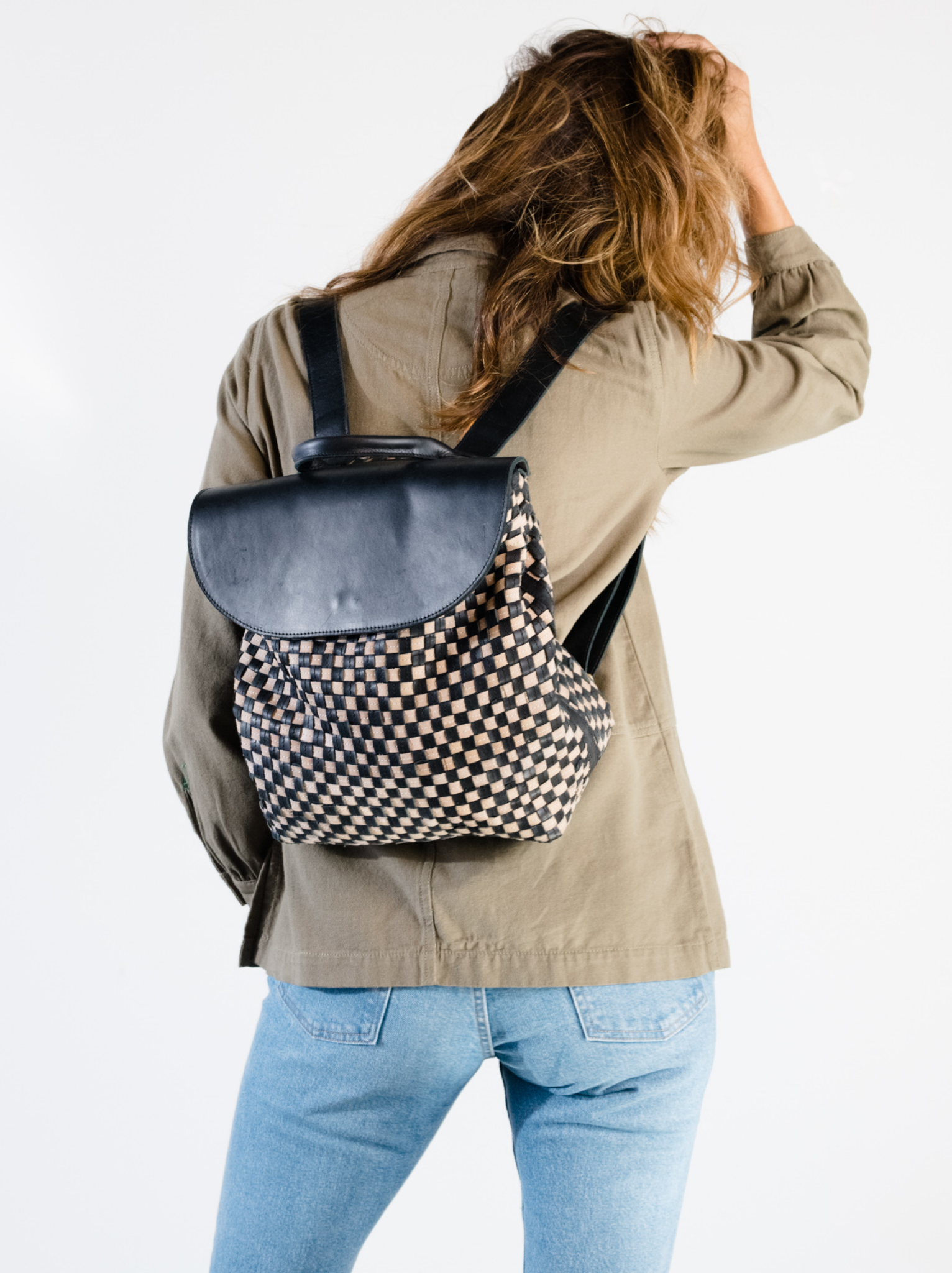 Woman wearing black and tan basketweave backpack on her back. #Color_Black/Tan