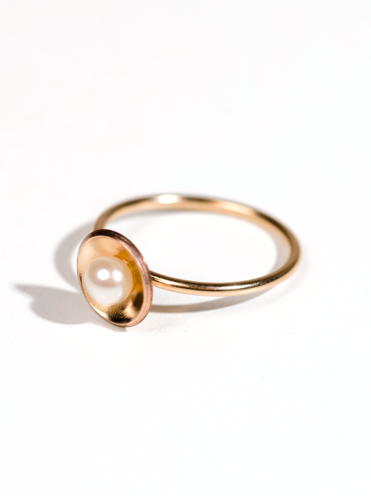 A gold-filled ring with a single pearl set in a bowl-shaped design, photographed on a white background.