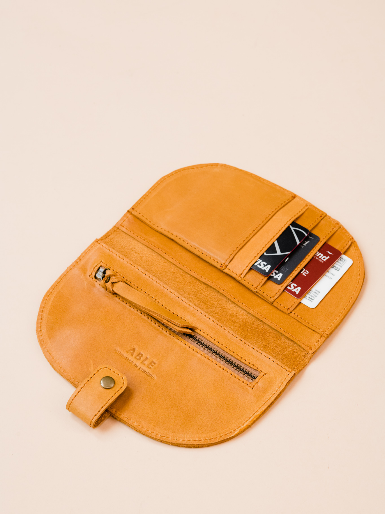Interior of cognac orange leather wallet with cards in card slots and a zipper pocket on a neutral background. #Color_Cognac