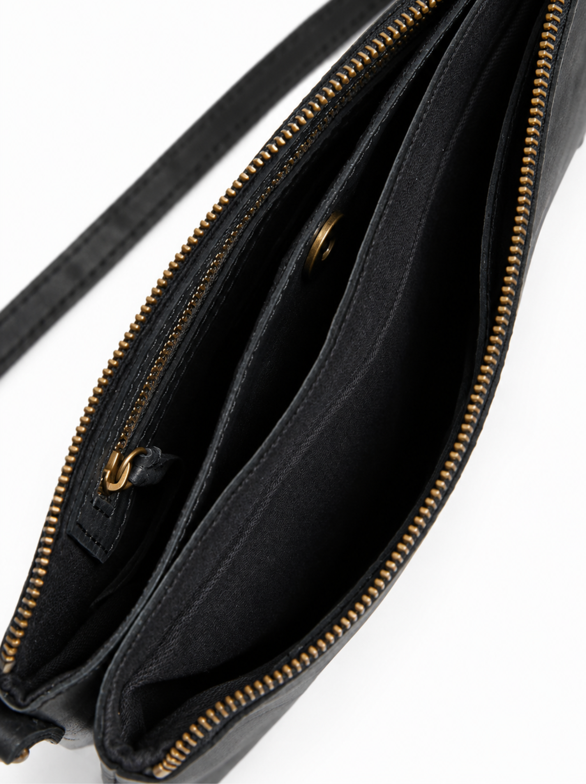 Close-up of the interior of a black leather crossbody bag with bronze-tone zippers and a black strap, shown on a white background. #Color_Black
