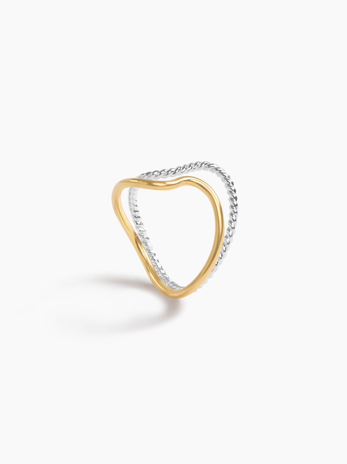 Standing view of a ring with a smooth gold band and twisted textured silver band on a white background.