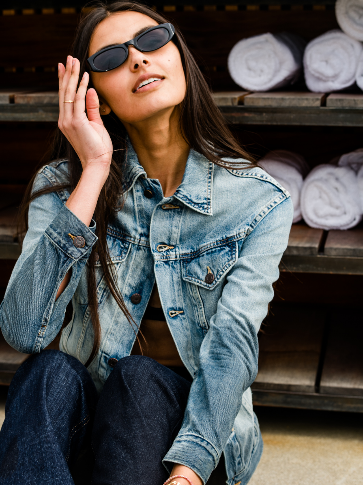 Woman wearing sunglasses and a The Merly Jacket sitting on a bench.