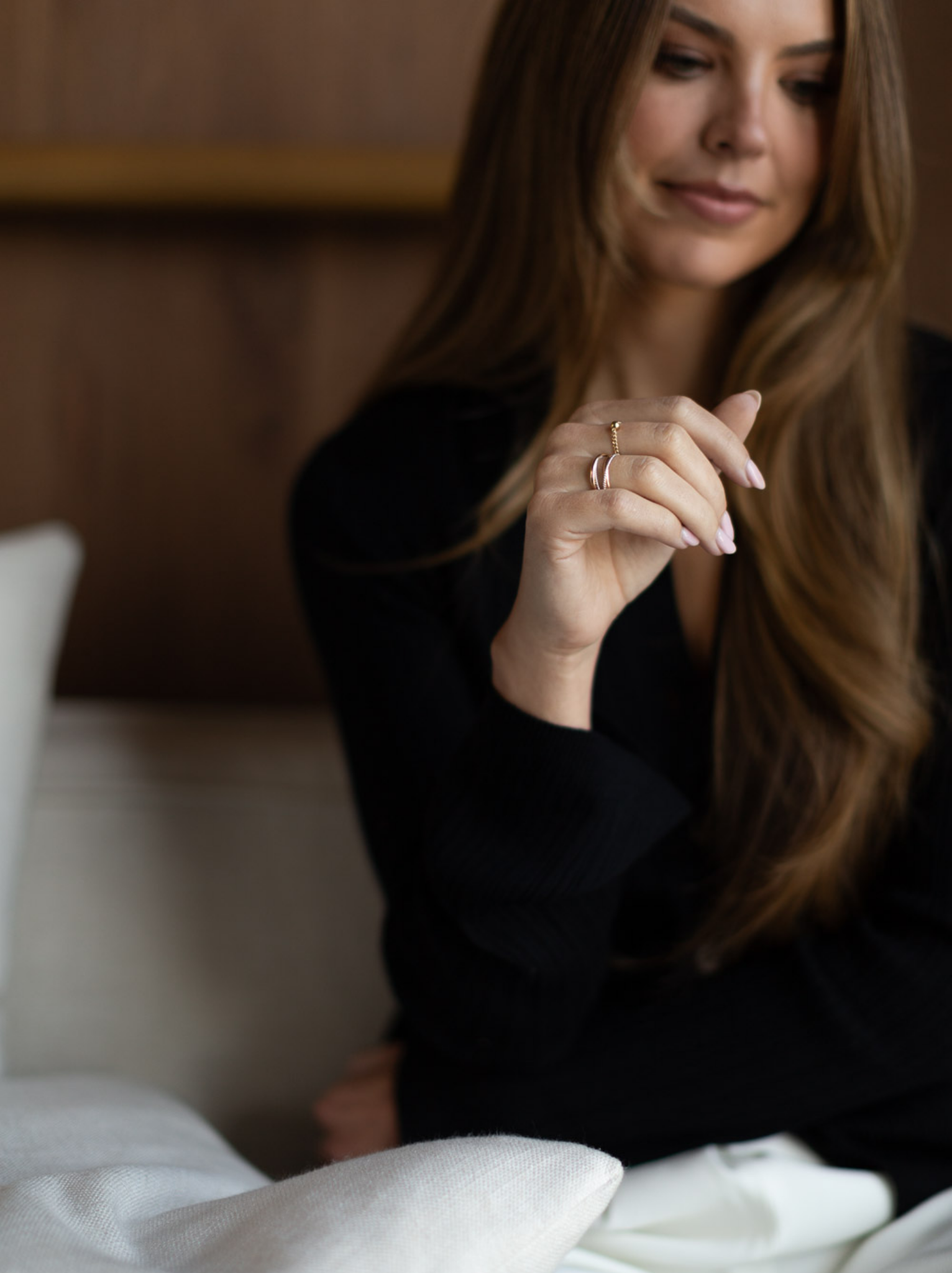 A woman's hand being held up wearing a gold chain ring with a ball bead accent.