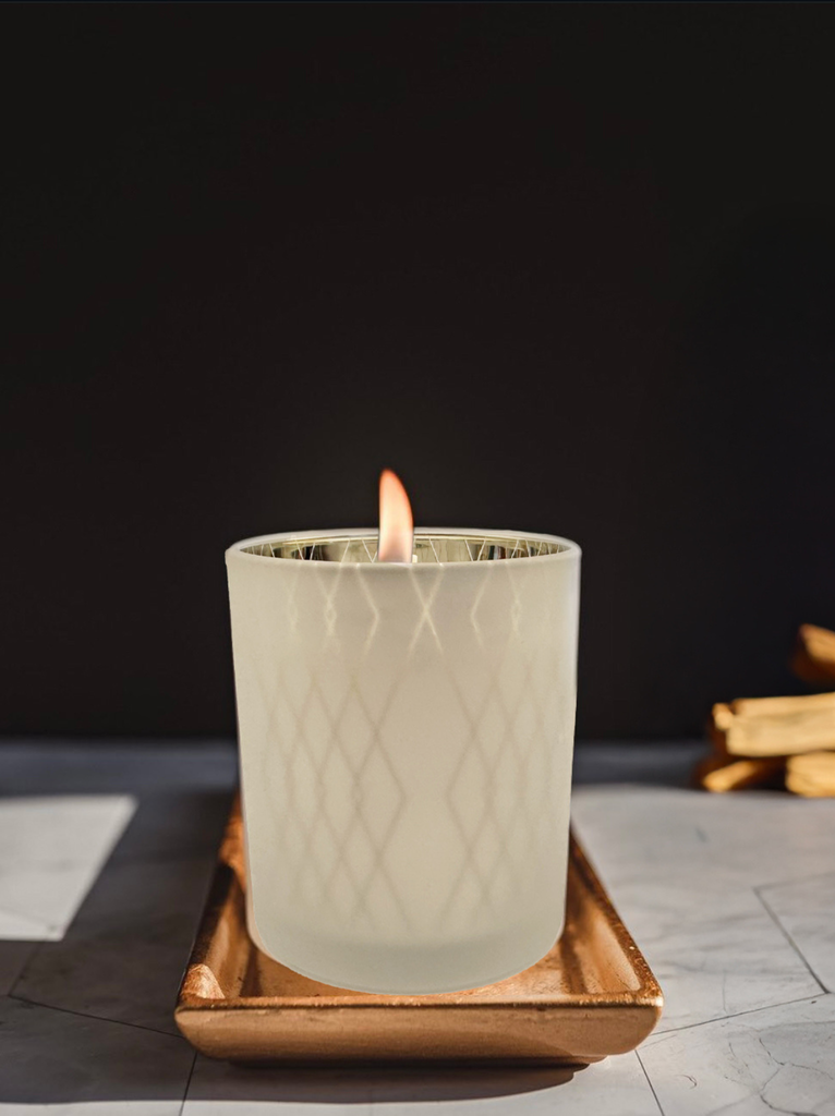 A single lit ABLE x Formulary55 candle in a clear glass jar, casting a warm light. 