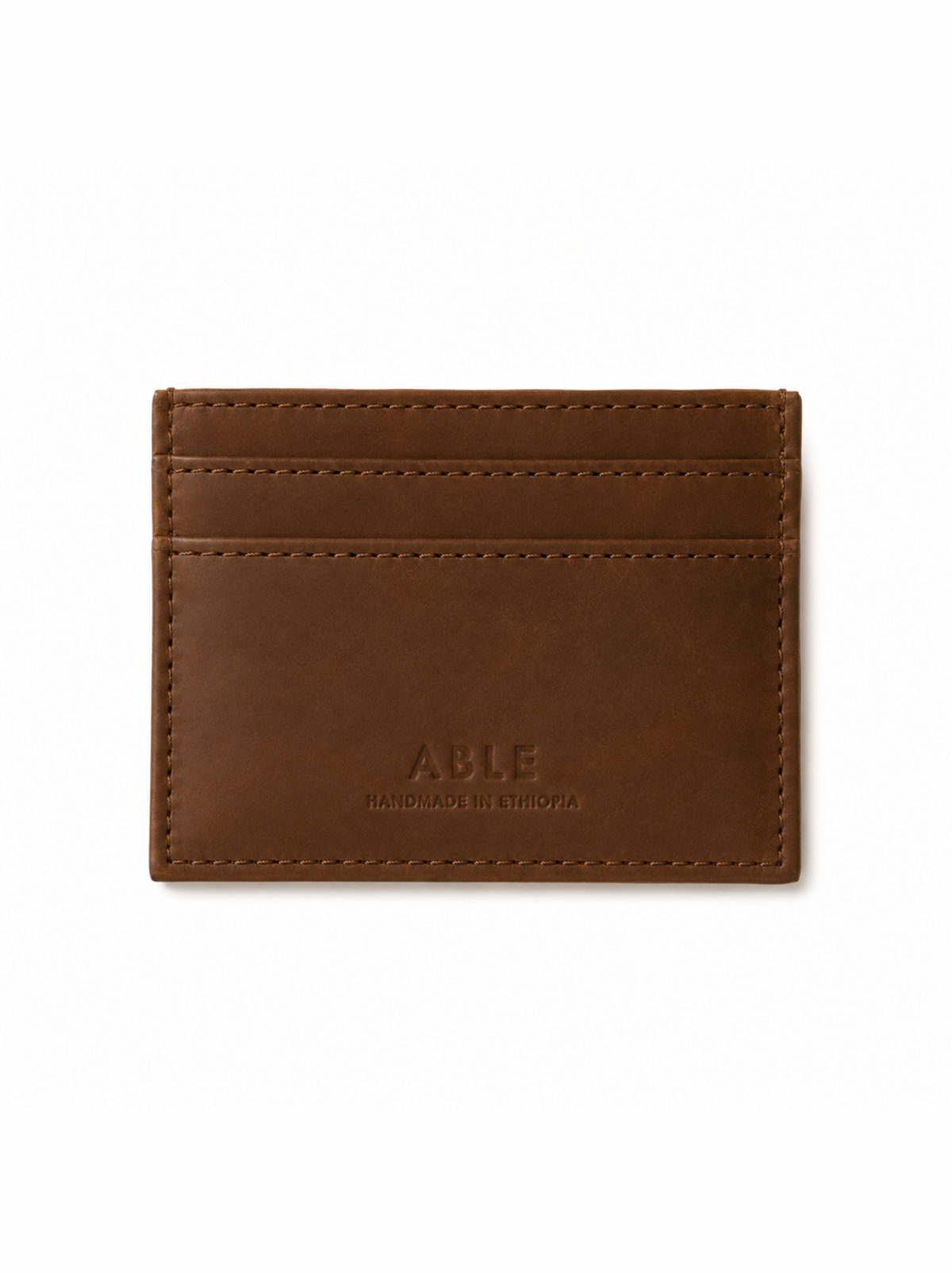 A brown leather card holder wallet with visible stitching and debossed 'ABLE' branding on the front, shown against a plain white background. #Color_Whiskey
