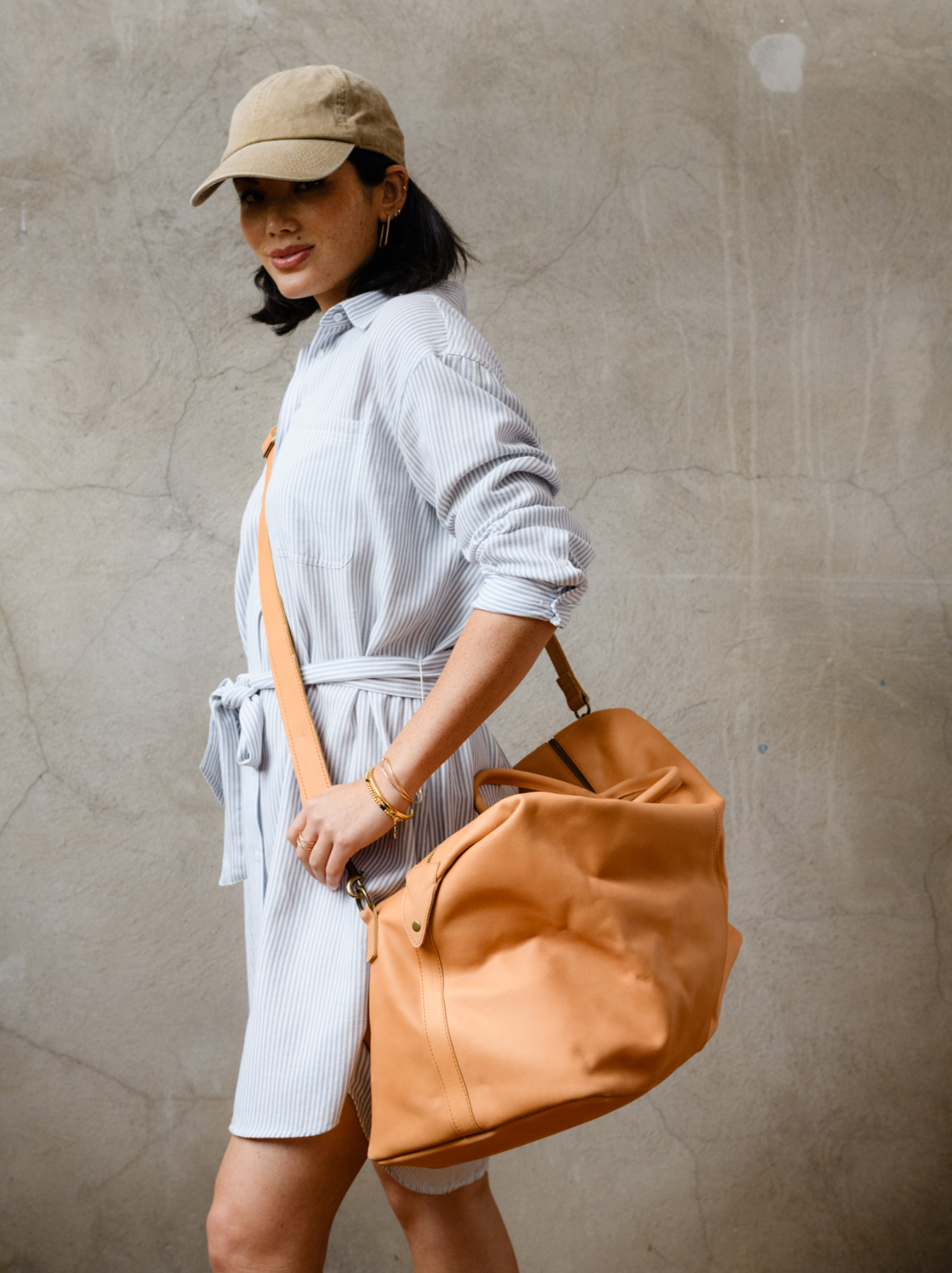A woman wearing the cognac weekender across her body with the detachable crossbody strap. #Color_Cognac