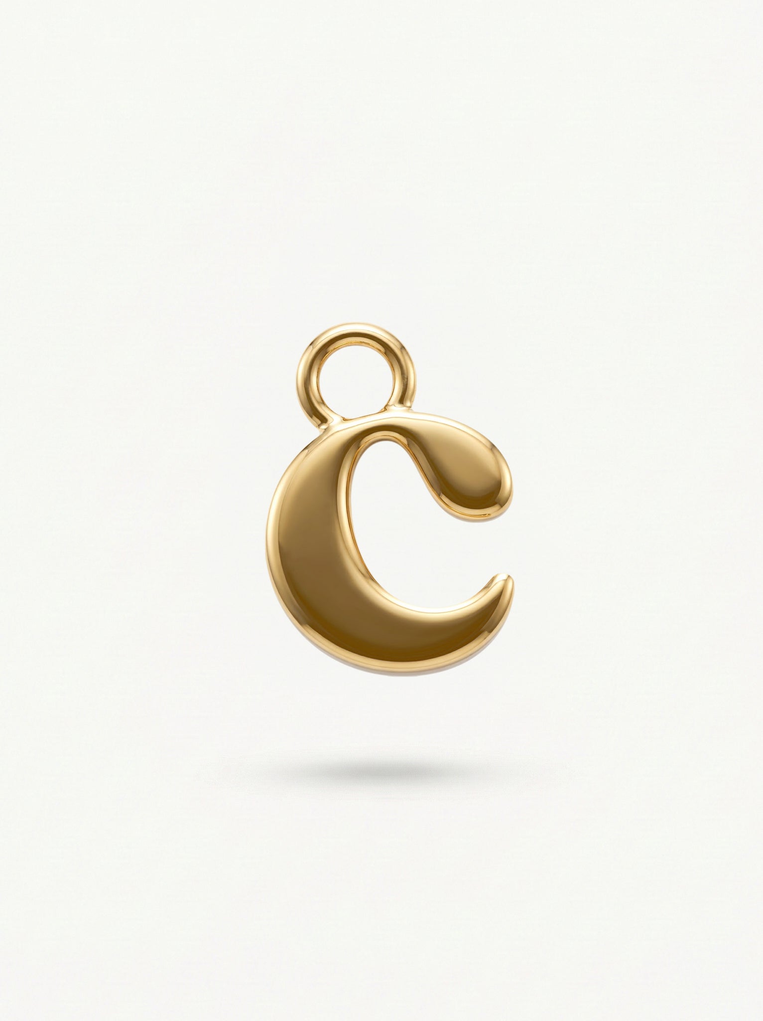 Initial Charm Gold Vermeil; Gold letter 'c' pendant on a light beige background