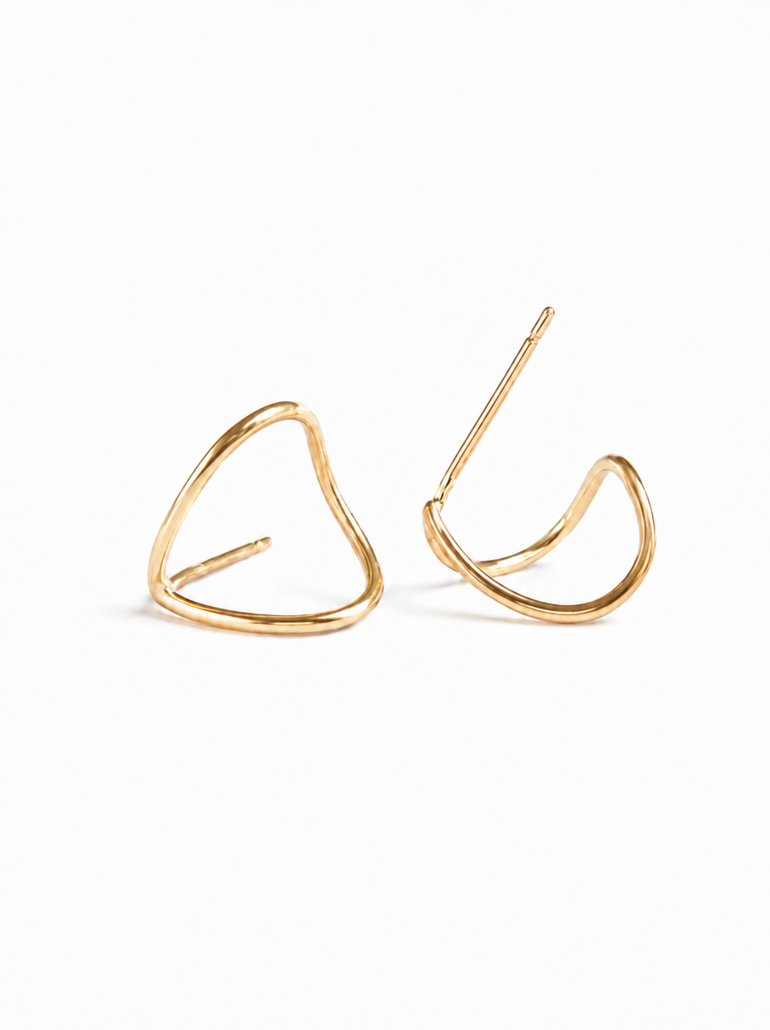 A pair of gold huggie earrings lying on their sides on a white background.