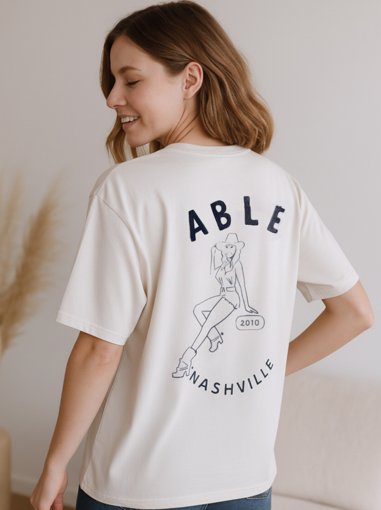 Person wearing a Easy Now Tee white t-shirt with 'ABLE Nashville' design on the back