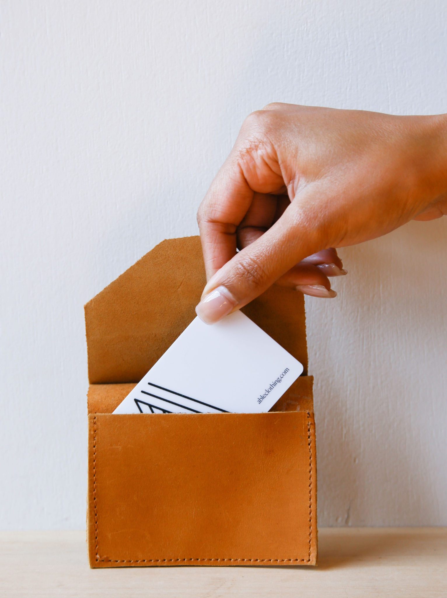 Hand holding Lita Leather Envelope cardholder with a white card against a neutral background