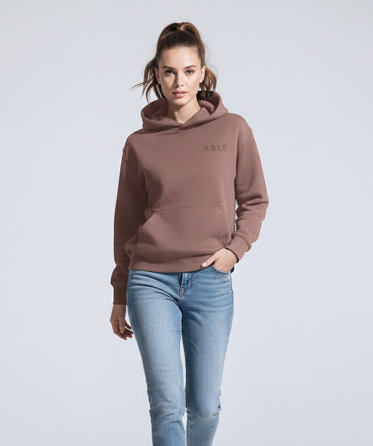 Woman wearing ABLE Signature Hoodie with 'ABLE' branding on a light gray background