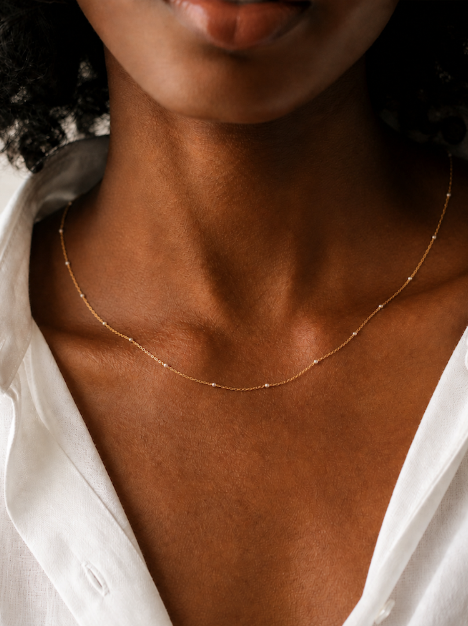 Close up of a woman wearing a gold chain necklace with silver bead design.