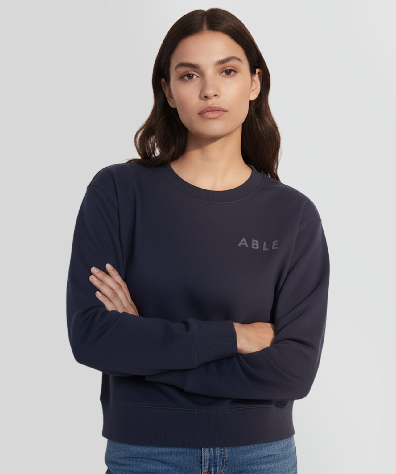 Woman wearing a ABLE Signature Crew with 'ABLE' logo on a light gray background