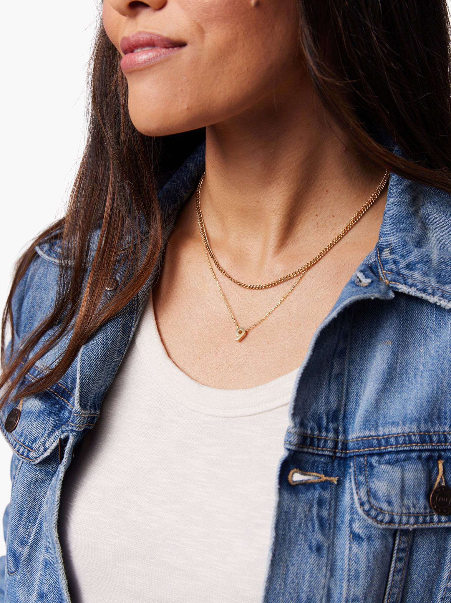 Woman wearing a Gold number 9 pendant on a gold chain layered with a chain necklace. #Color_Gold Vermeil